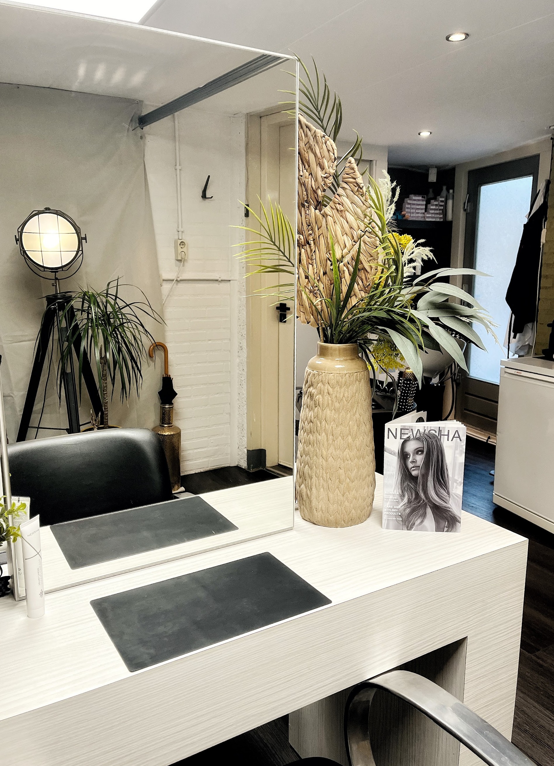 De spiegeltafel met een vaas droogbloemen en een stoel