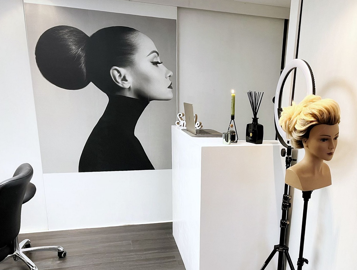 Een zwart-witposter aan de wand, een oefenhoofd met blond haar en een ringlamp